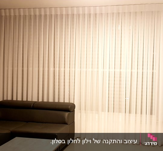 וילון לבן שקוף תלוי על חלון גדול